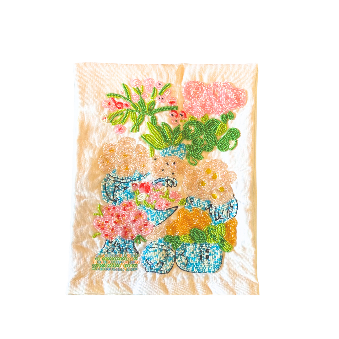 White cotton tea towel featuring a colorful hand-beaded design of traditional blue-and-white ginger jars filled with blooming florals and lush greenery.