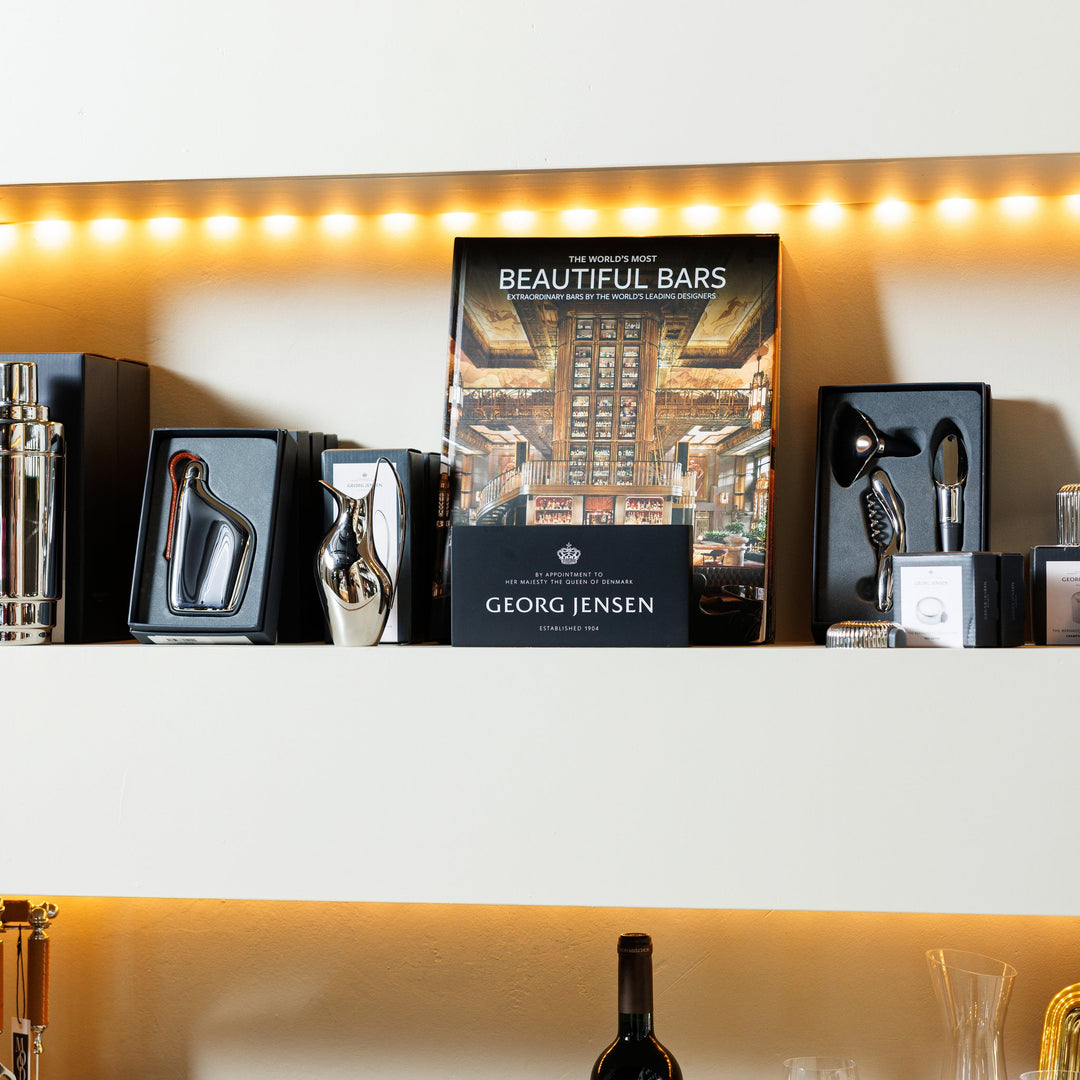 Georg Jensen barware and Beautiful Bars book on a lit shelf at Mood by DMJ