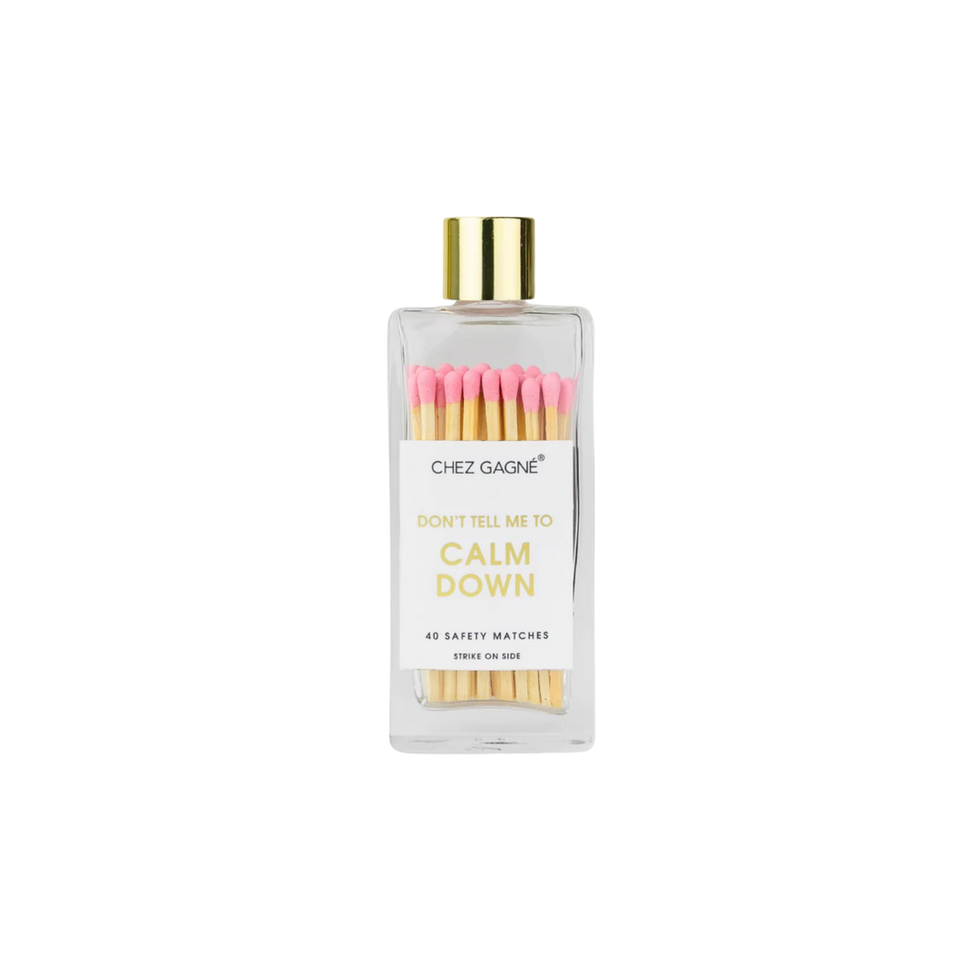 Glass bottle safety matches with pink tips and gold lid labeled Don’t Tell Me To Calm Down displayed on a clean background