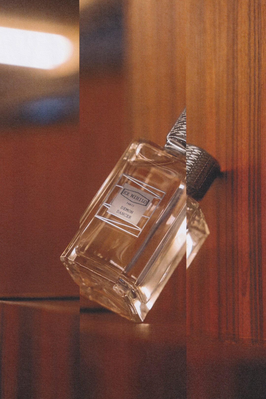 Ex Nihilo Demon Dancer Eau de Parfum bottle with its signature silver cap tilted against warm wood paneling