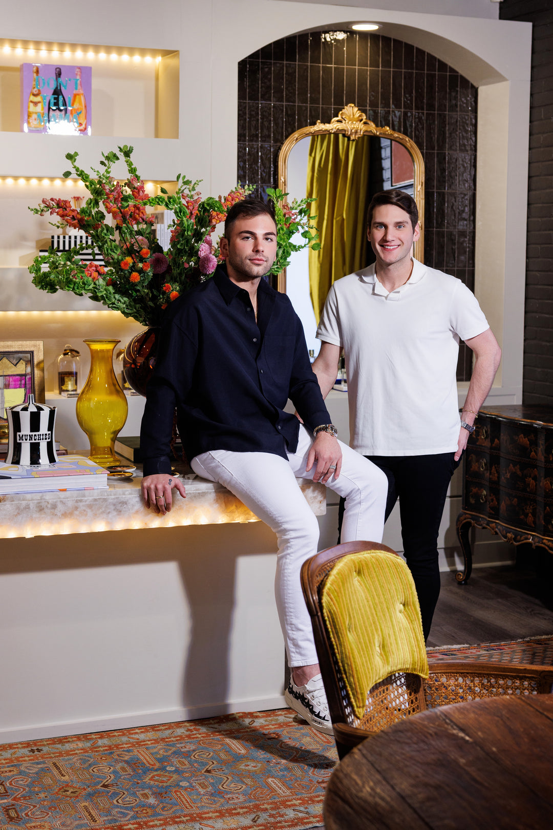 Two people posing inside the Mood by DMJ boutique in Lafayette with lush florals and a gold mirror