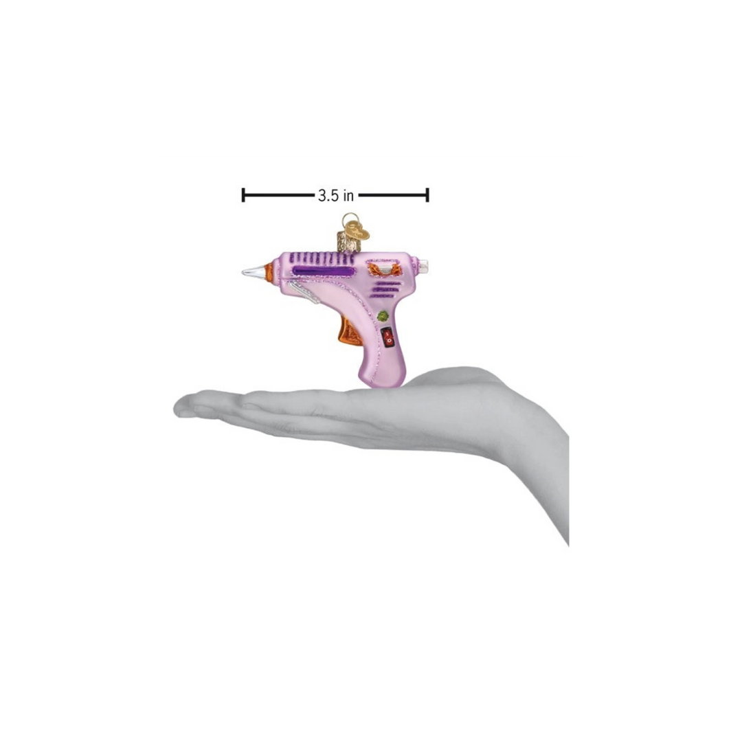 Hot Glue Gun glass ornament by Old World Christmas with silver and glitter accents hanging on a Christmas tree at Mood by DMJ in Louisiana.