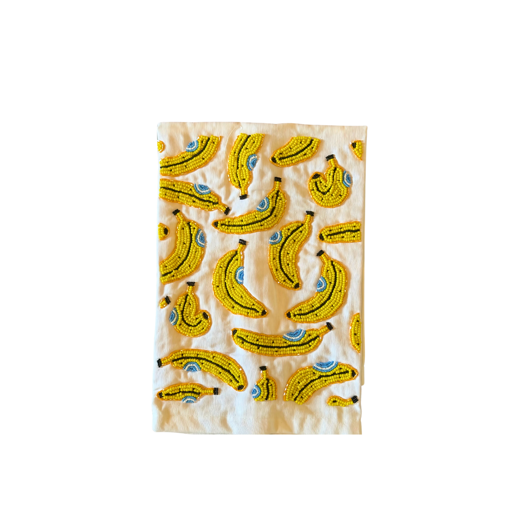 White cotton tea towel with hand-beaded yellow banana designs, playful kitchen décor accessory.
