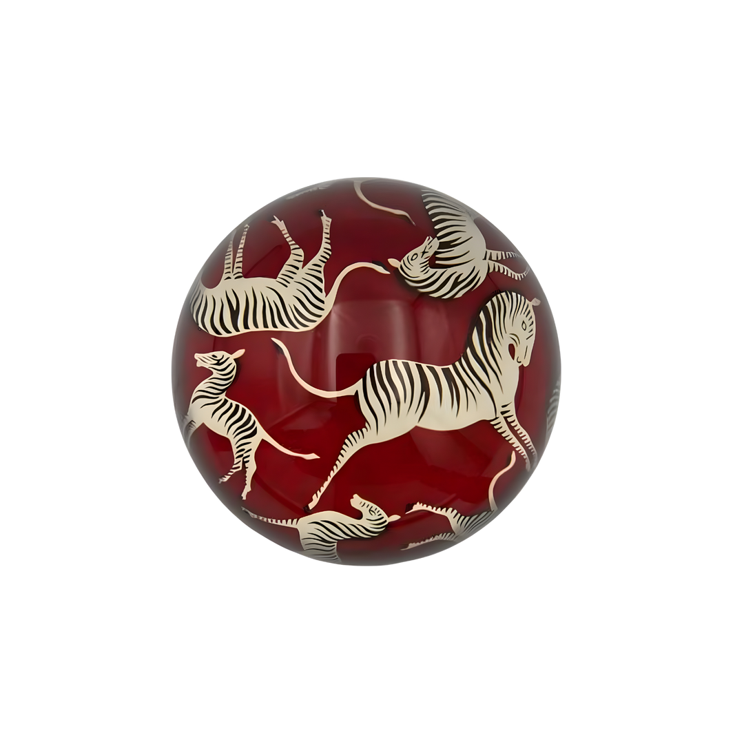 Zebra glass paperweight with ivory zebras on red background under dome at Mood By DMJ Lafayette Louisiana