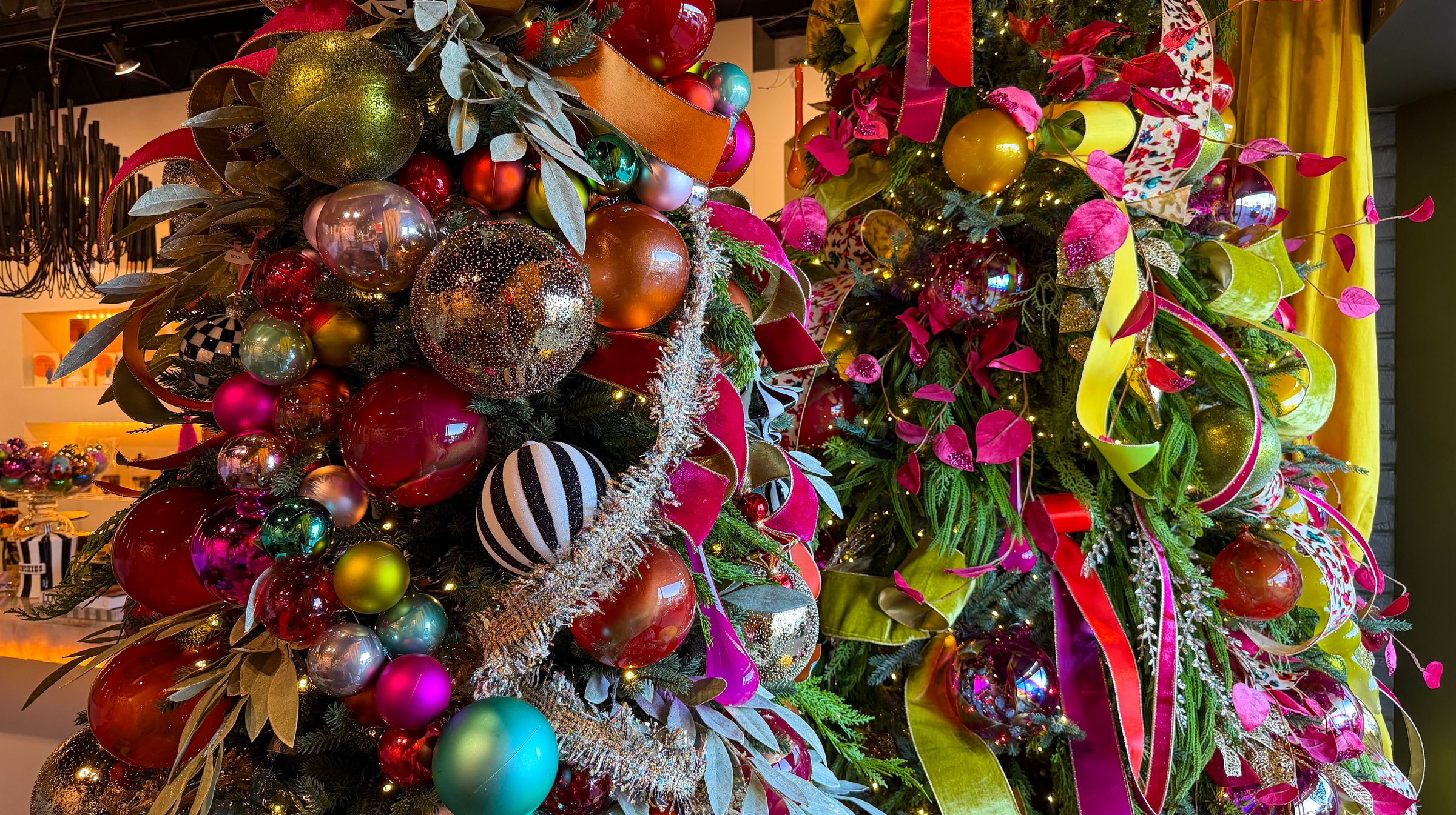 Decorative Christmas trees with colorful Jim Marvin ornaments and D. Stevens ribbons at Mood by DMJ in Lafayette, LA.