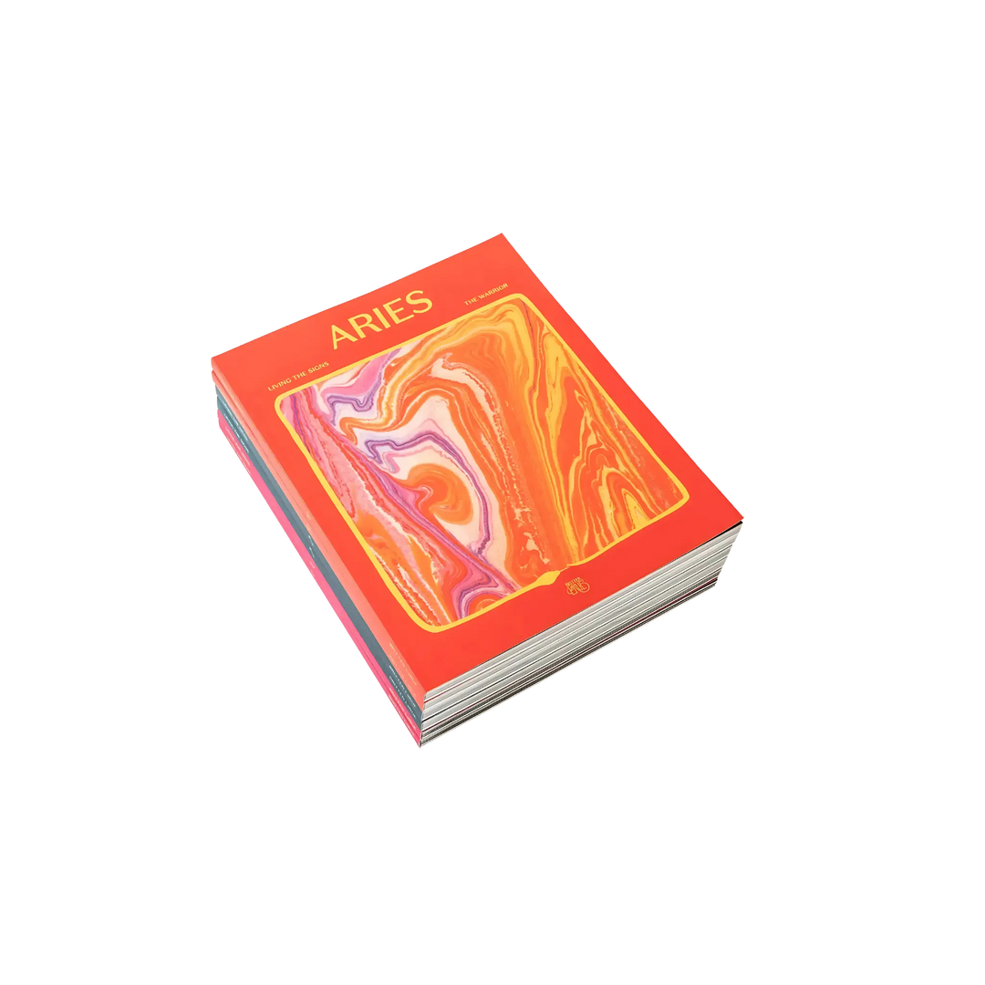 Stack of Aries: The Warrior astrology workbooks by In Case of Emergence with a red and gold marbled cover