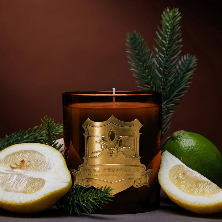 Grove luxury citrus and green tea candle by DMJ Home Fragrance in signature glass vessel styled with lemon, lime, and evergreen branches