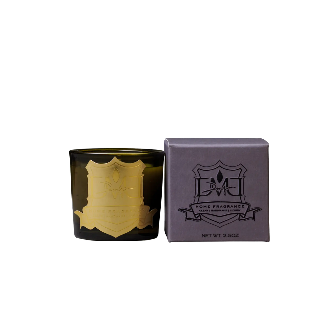 Woods Votive by DMJ Home Fragrance, black candle with gold emblem and matching box on a white background