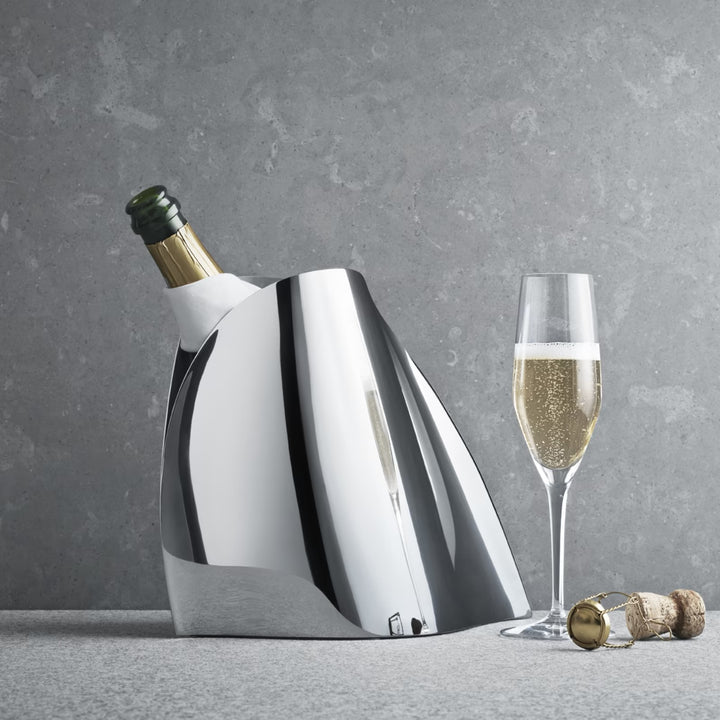 Georg Jensen Indulgence stainless steel champagne cooler chilling a bottle beside a filled champagne flute