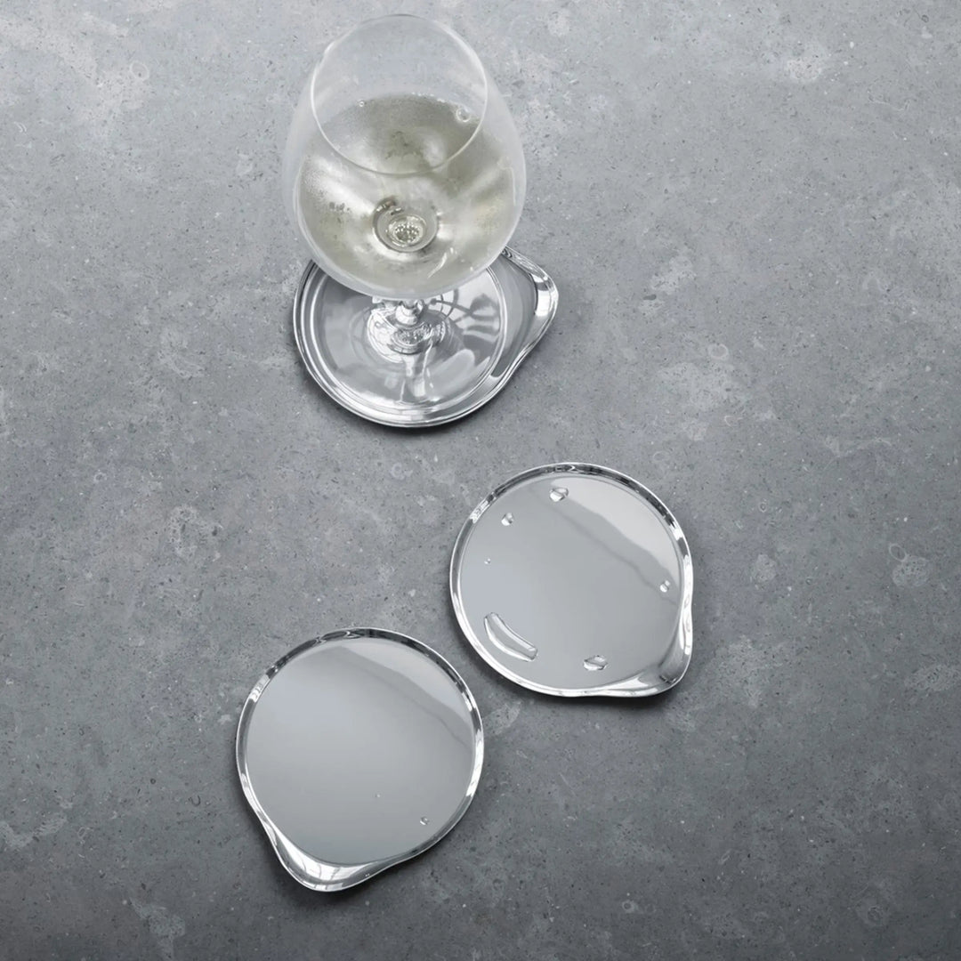 Georg Jensen stainless steel wine coasters styled with a wine glass on a stone table top