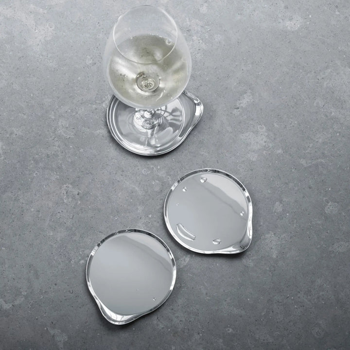 Georg Jensen stainless steel wine coasters styled with a wine glass on a stone table top