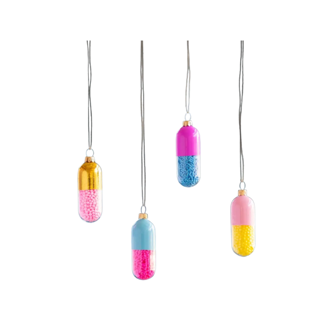Glitterville Happy Pill capsule ornaments in gold, pink, light blue, and yellow