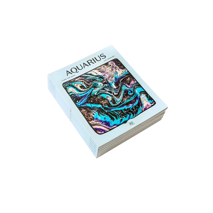 Living the Signs: Aquarius astrology workbook by Britten LaRue, angled paperback with blue marbled cover on black