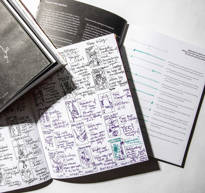Open Living the Signs workbook with a hand-drawn tarot journal grid and a tarot spread worksheet