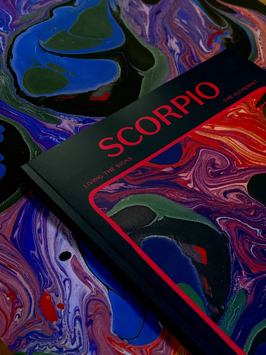 Close up of the Living the Signs: Scorpio cover by Britten LaRue on a sheet of marbled paper