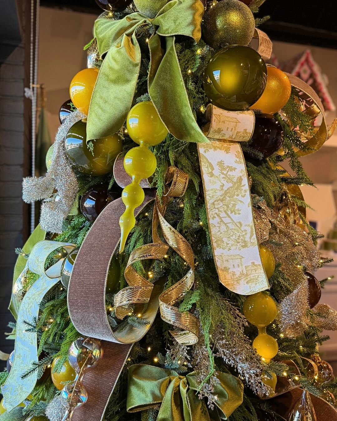Close-up of a Christmas tree with chartreuse velvet bows, toile ribbon, amber and olive glass ornaments by Mood by DMJ