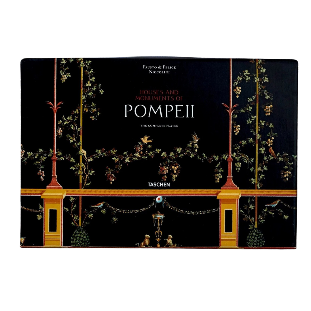 Houses and Monuments of Pompeii XXL book by TASCHEN, black Pompeian fresco cover with gold columns, garlands, and birds